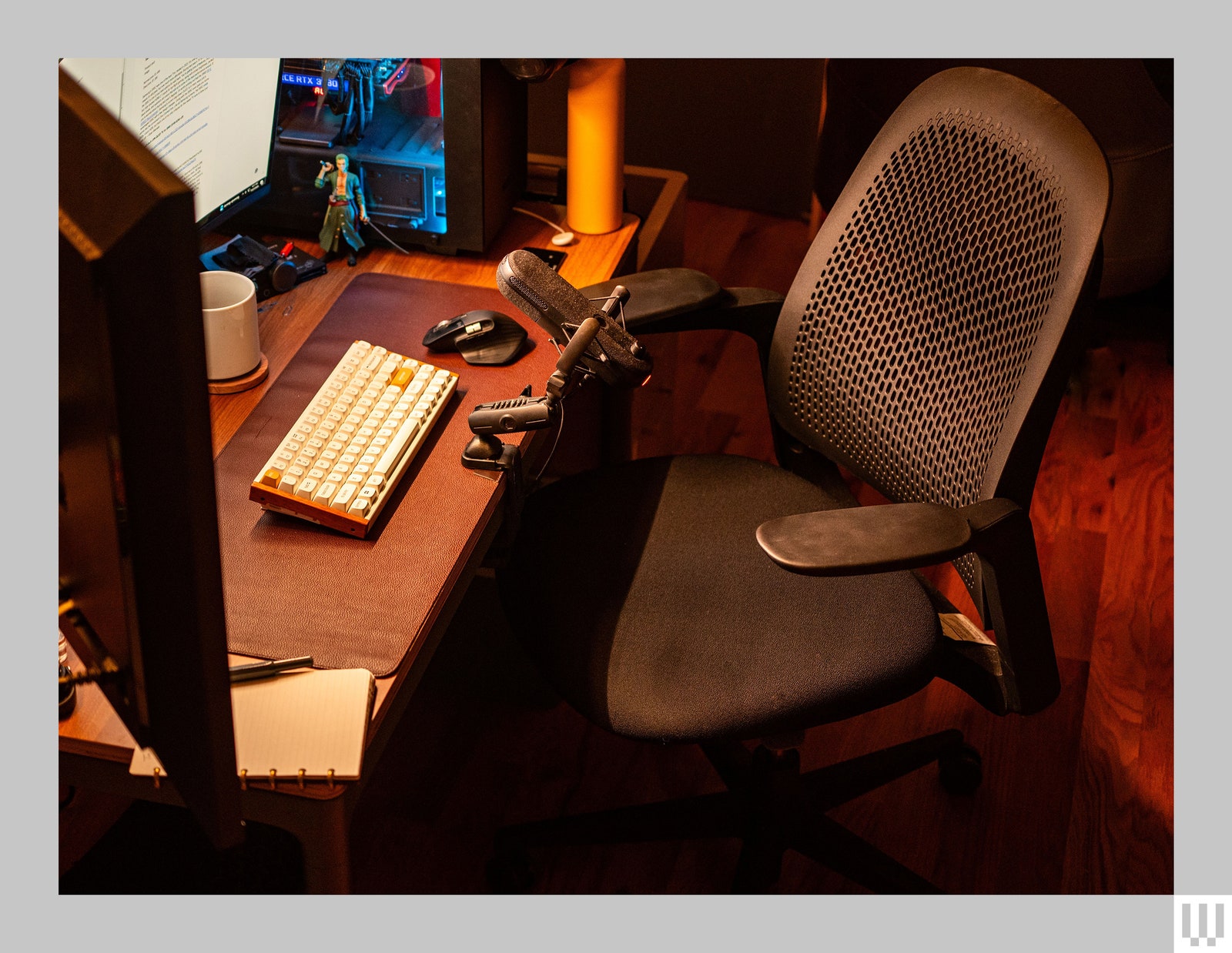 Haworth Breck Office Chair a black chair with mesh backing and arm rests beside a dimly lit work desk