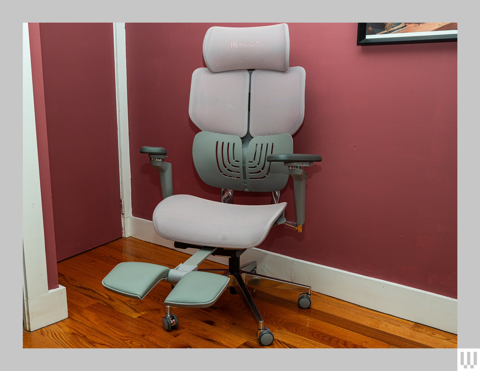 Front view of beige office chair in a room soft pink walls and hardwood floors. The chair has a headrest two shoulder...