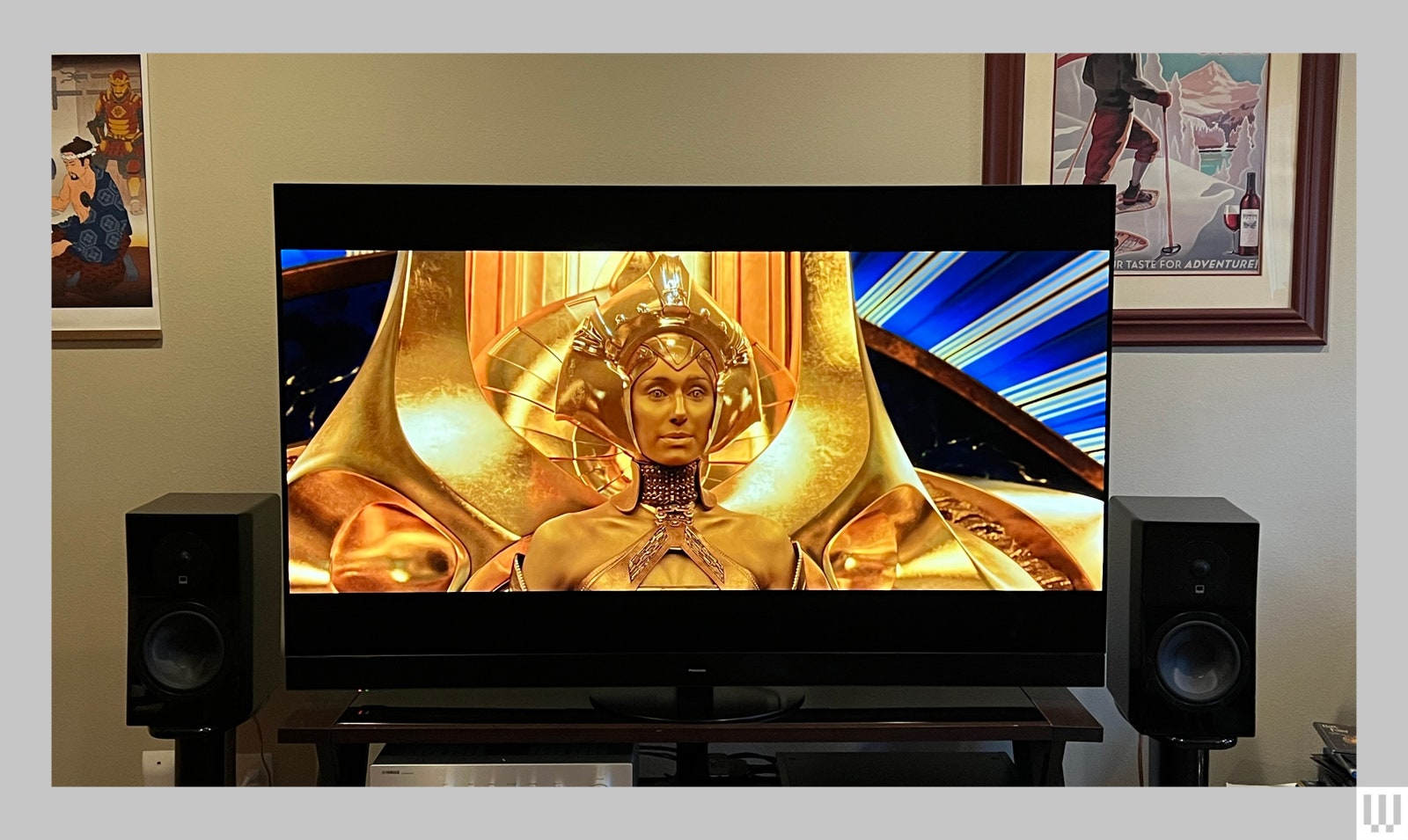 Front view of a Panasonic Z95A OLED TV the screen showing a film scene of a person in all gold in front of a gold throne