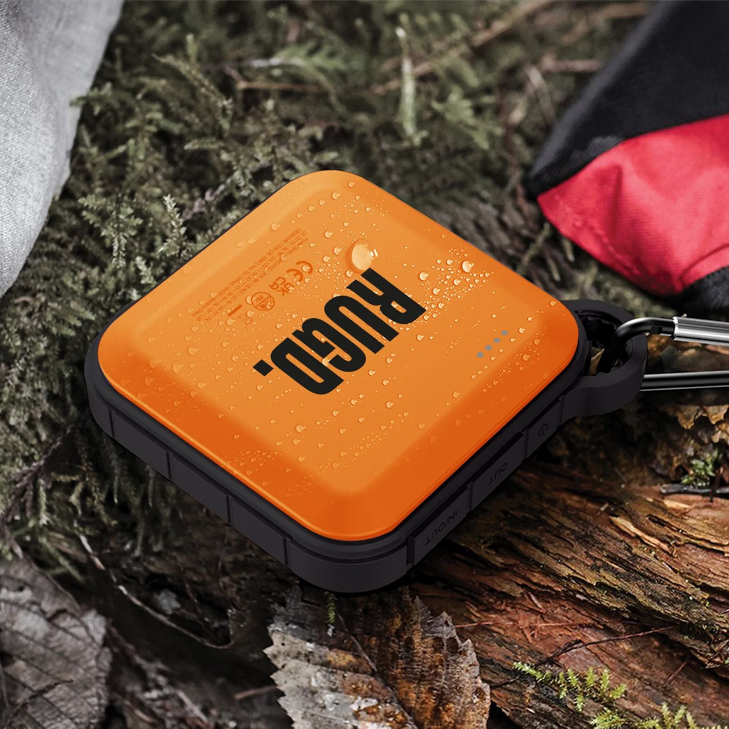 RUGD power brick charger placed on tree bark and leaves with water droplets on top