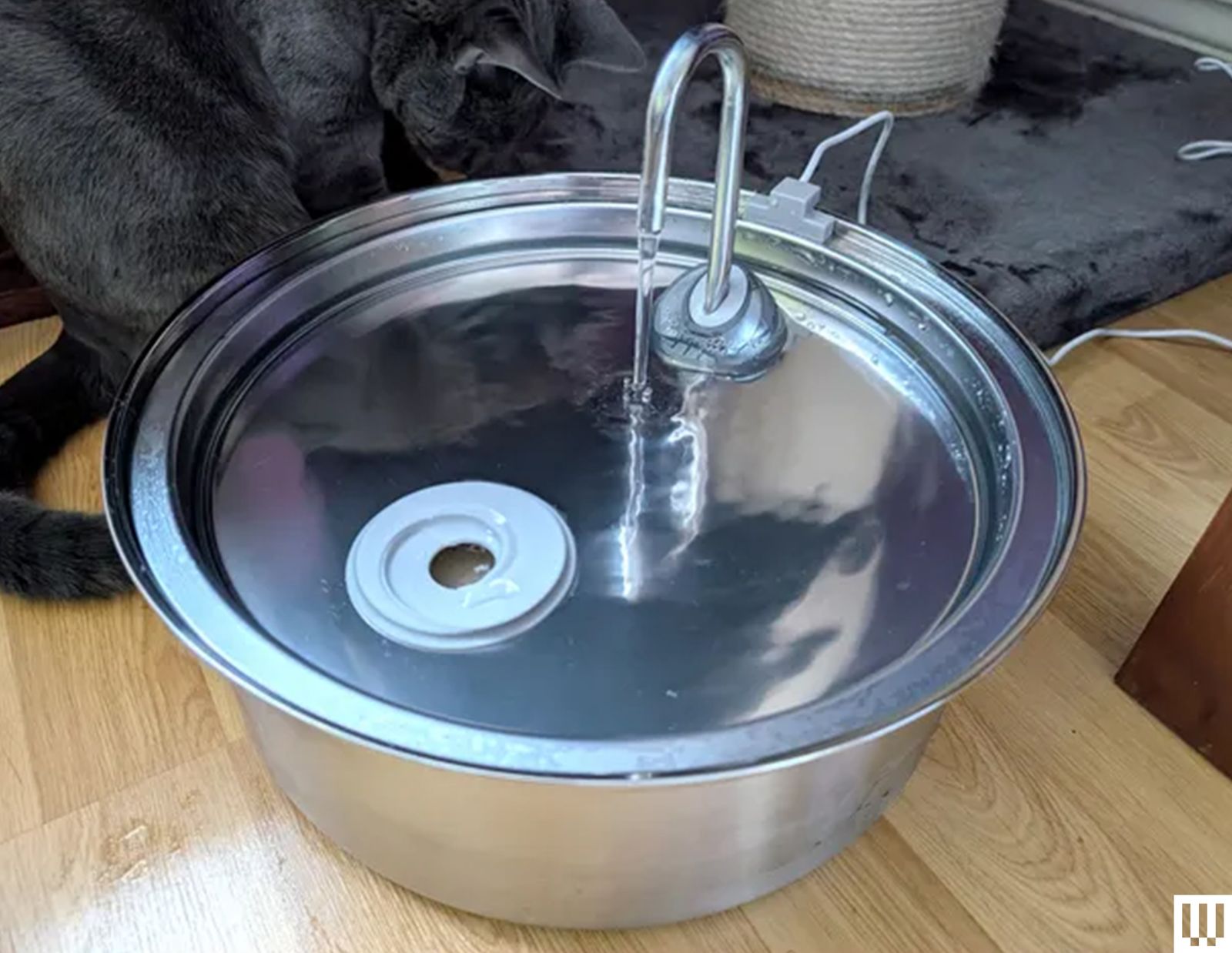 Oneisall Stainless Steel Pet Fountain a metallic bowl with circular pan on top where water flows onto from a curved spout