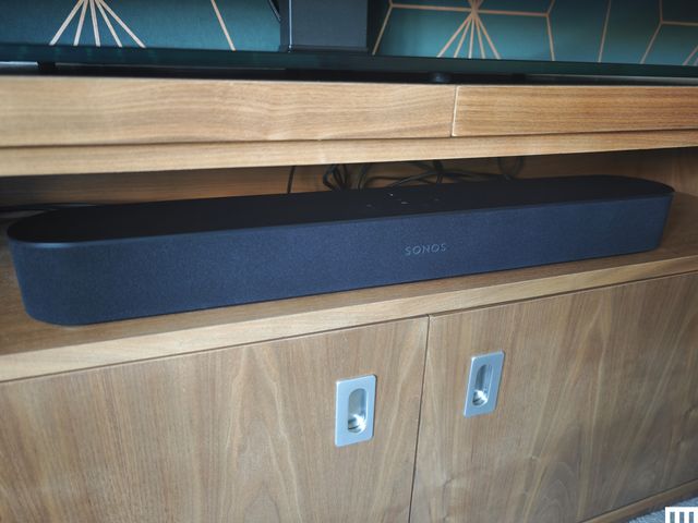 Front view of Sonos Beam Gem 2, a long grey speaker on the shelf of a light brown media console