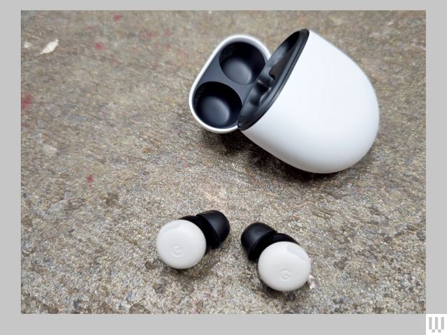 2 white earbuds beside an open white oval-shaped case