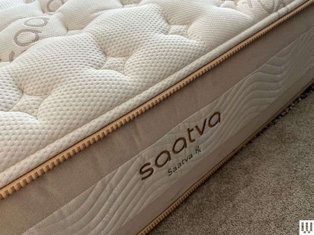 Side-view of Saatva TX, a thick mattress with white top and beige trim