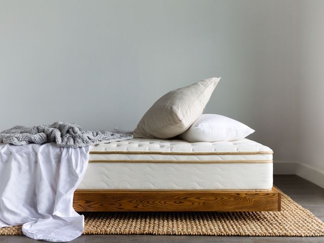 Saatva Classic Mattress on a bed frame with sheets and pillows