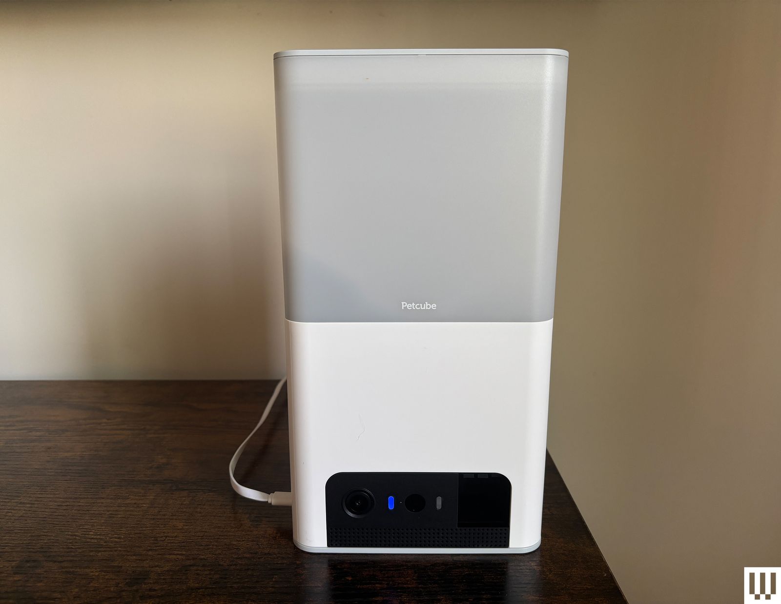 Large rectangle white pet camera with feeding tank on top sits on a wood ledge with cream wall background