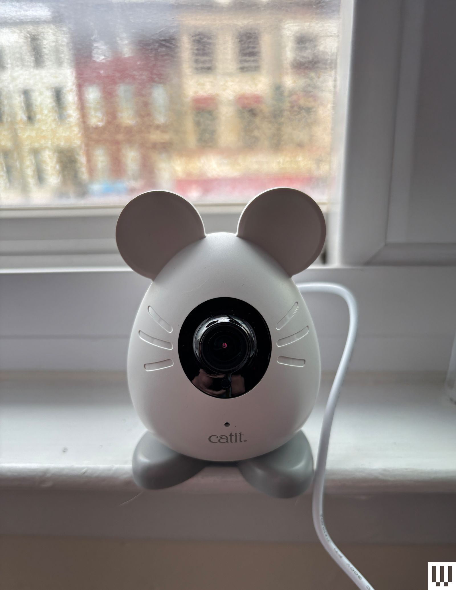 White mouseshaped pet camera sits on a white windowsill.