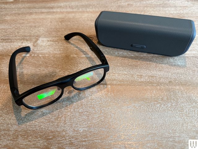 A black pair of smart glasses beside a grey case