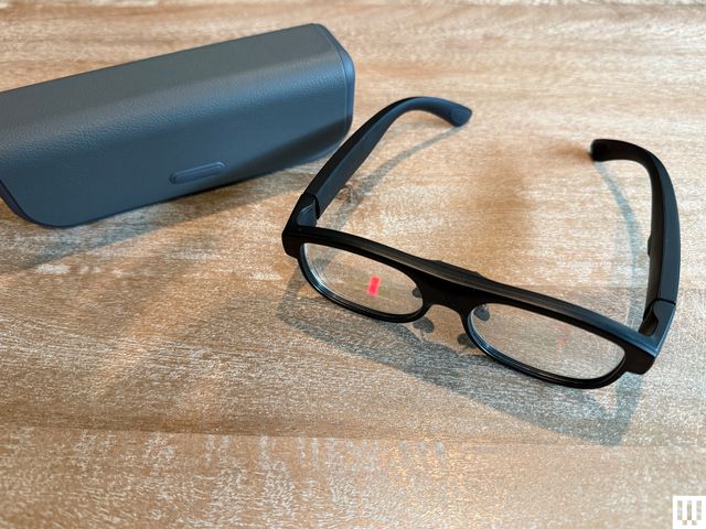 A black pair of smart glasses beside a grey case