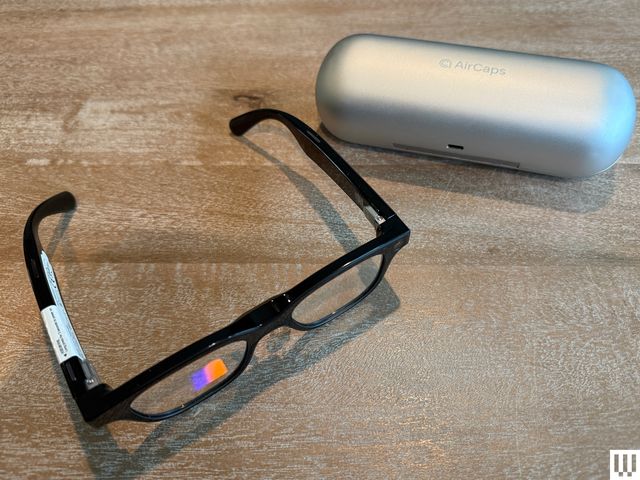 A black pair of smart glasses beside a silver case