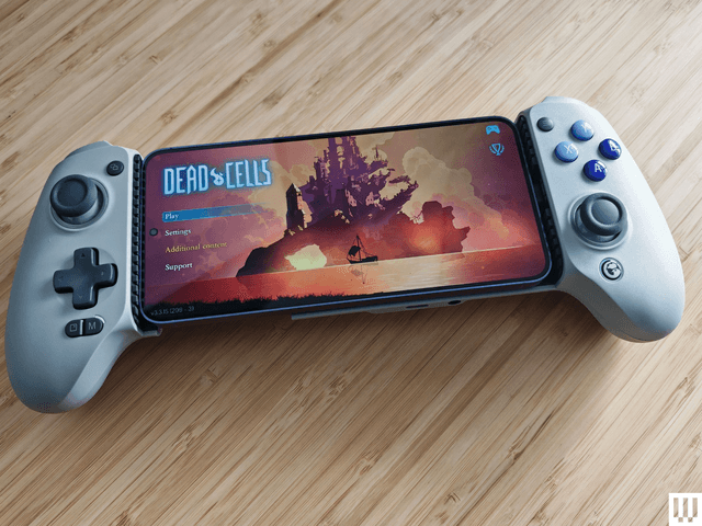 Grey video game controller with long rectangular console in the middle. Left side has a joystick and directional pad. Right side has 4 buttons and a joystick.