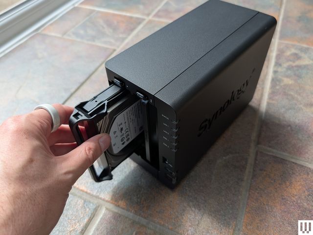 Person pulling a hard drive out of a black computer device